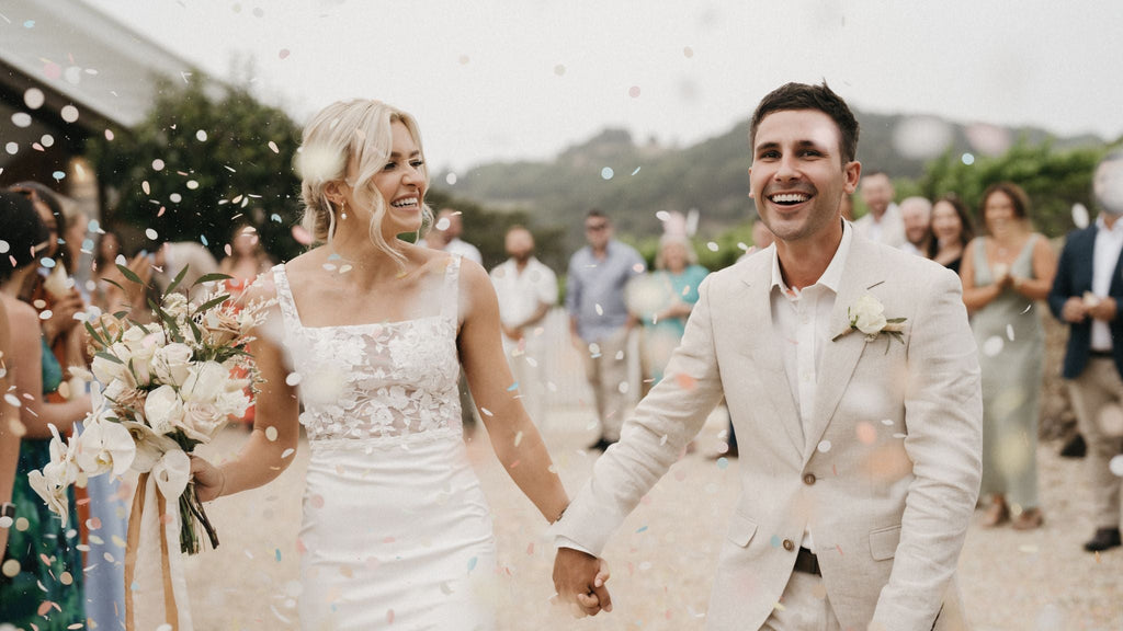 Eco-friendly confetti flutters as smiling newlyweds hold hands in joy.