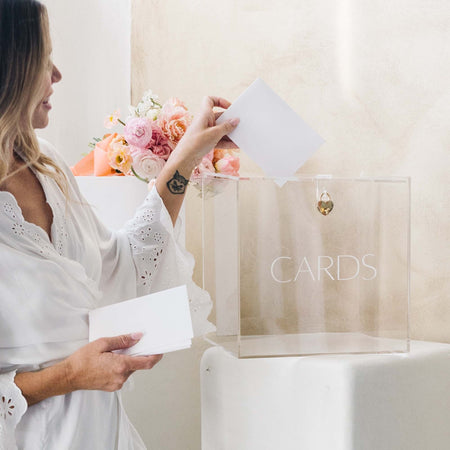 Woman putting a card into an acrylic box with a subtle 'cards' on the front box