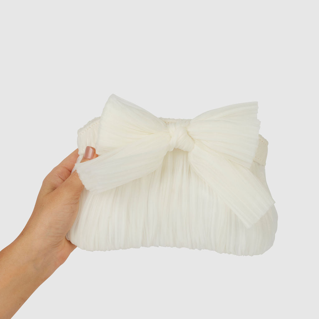 White pleated clutch bag featuring a stylish bow detail, perfect for a chic evening out.